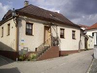 A small, older house with a brown roof and stairs in a quiet street.