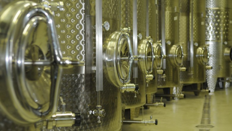 Row of stainless steel tanks in a wine cellar.