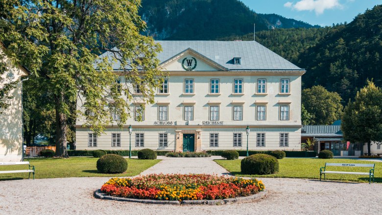 Reichenau Castle with garden and flowerbed in the foreground.