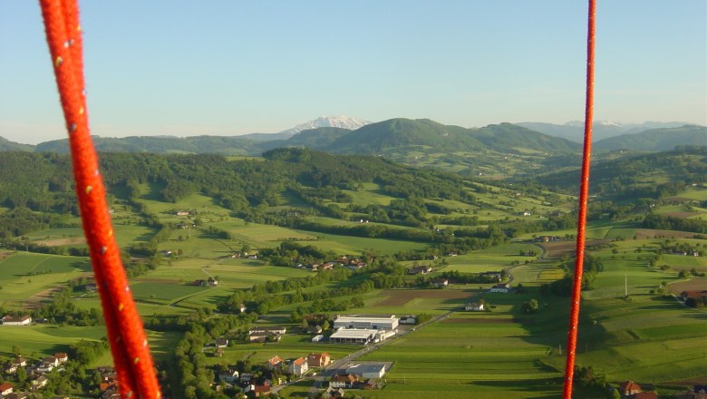 Landscape in the Mostviertel from a hot air balloon with red ropes in the foreground.