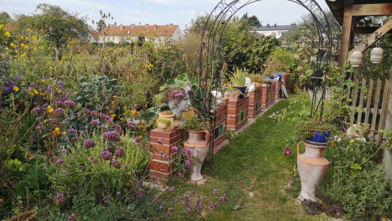 A colorful garden with flowers, brick wall and decorative vases.