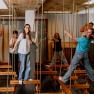 Children play on an indoor ropes course with wooden platforms.