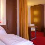 Hotel room with double bed, red carpet and modern furnishings.