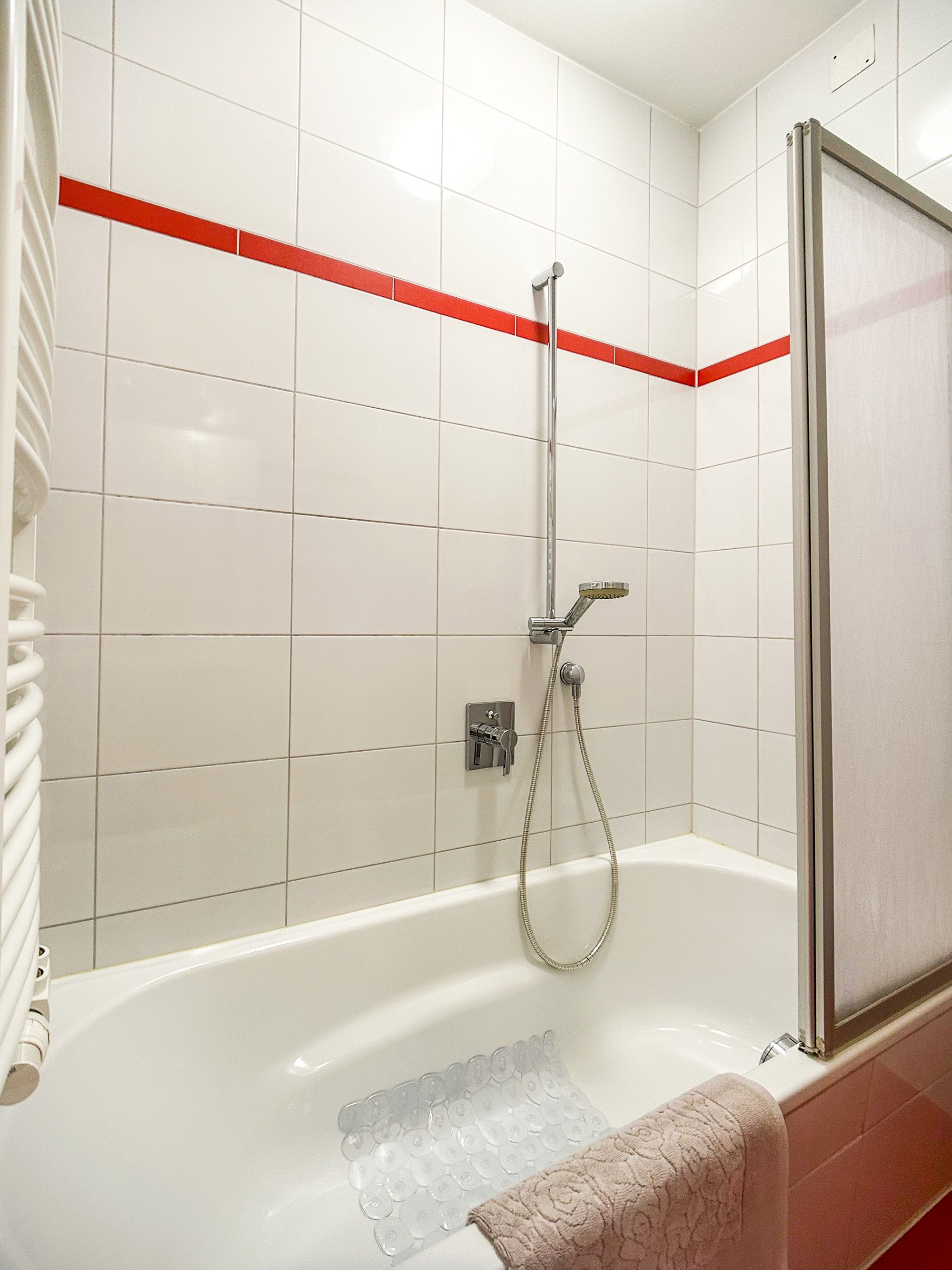 Bathroom with bathtub, shower head and red tiles.