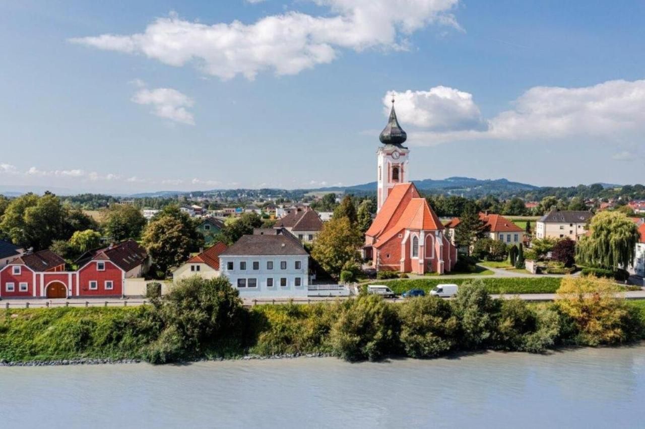 Landscape view of Persenbeug-Gottsdorf with church and river in the foreground.
