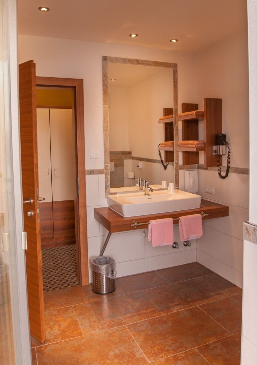 Modern bathroom with washbasin, mirror, towels and hairdryer.