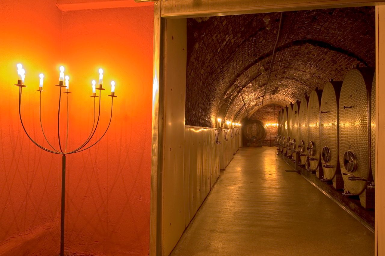 Wine cellar with illuminated metal tanks and candlesticks.
