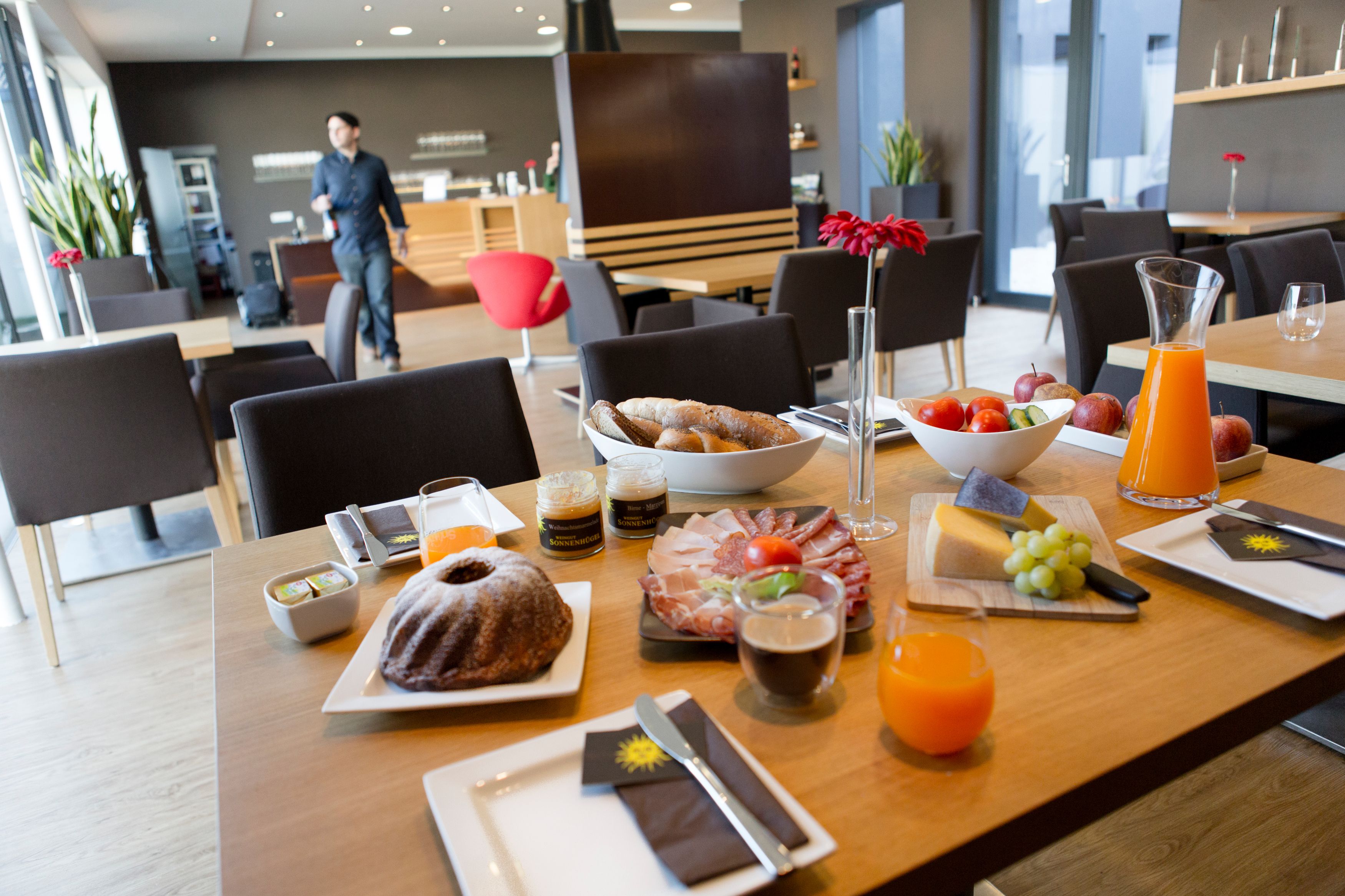 Breakfast table with pastries, cold cuts, cheese, fruit and juice in a modern café.