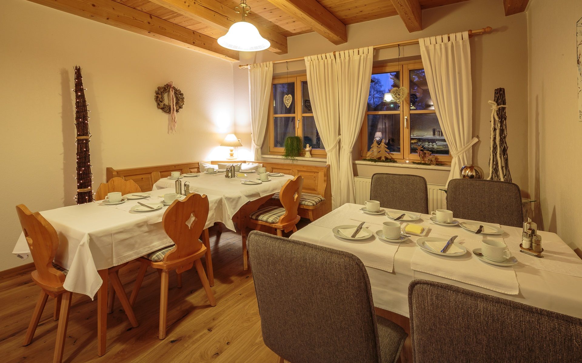 Cozy breakfast room with laid tables, wooden furniture and decorations.