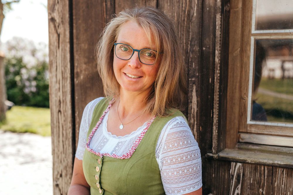 Sonja Langthaler in traditional dress in front of a wooden wall.