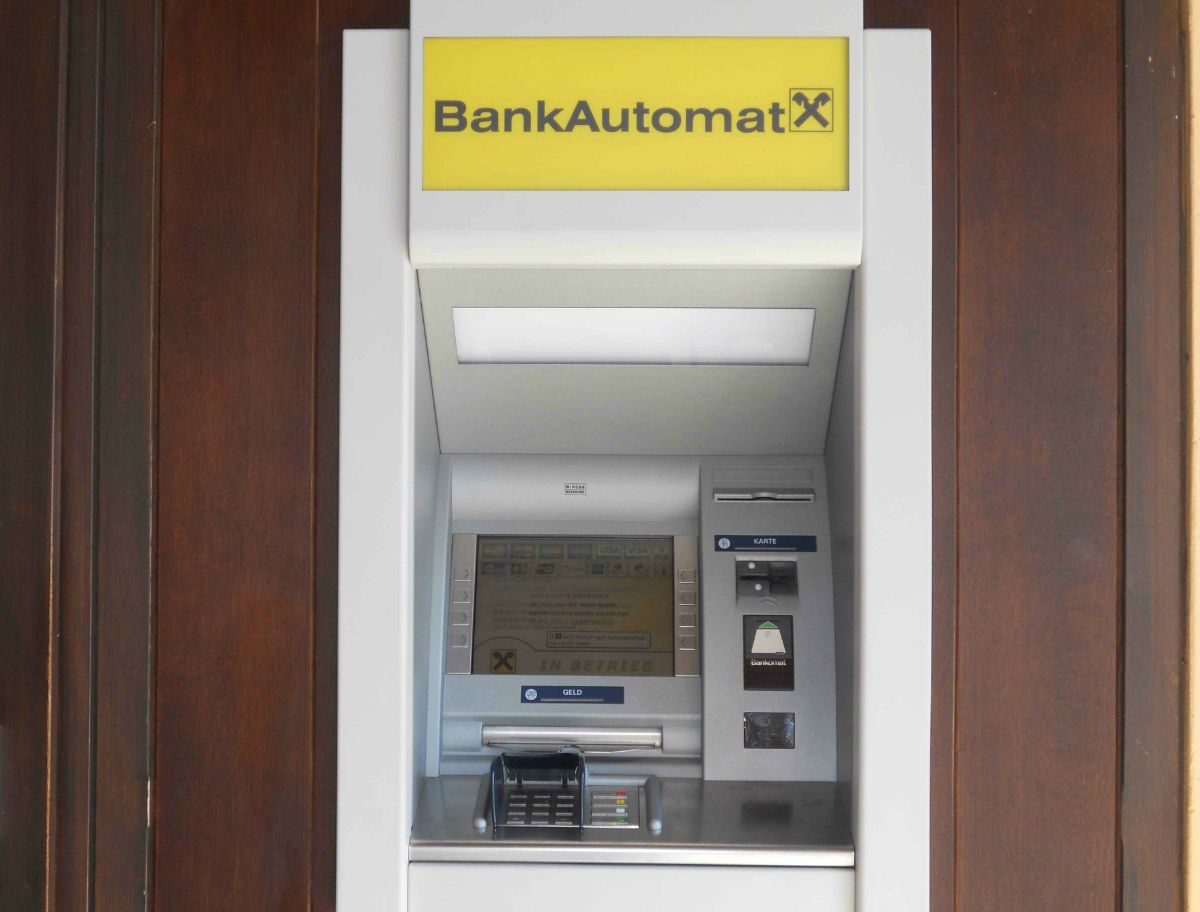 An ATM with a yellow sign and Raiffeisen logo.