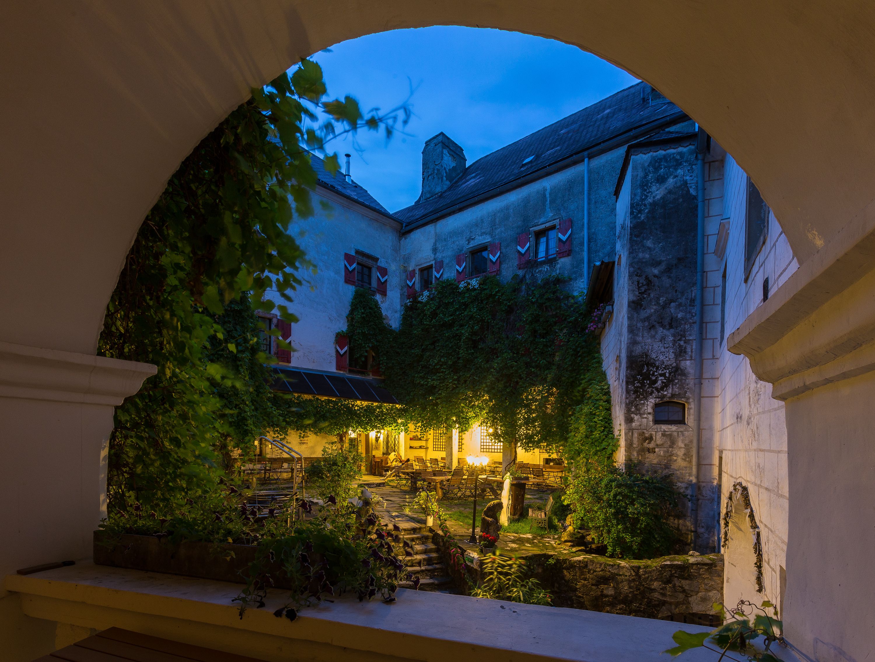 Inner courtyard of Plankenstein Castle at dusk, illuminated with warm light, surrounded by ivy and old walls.