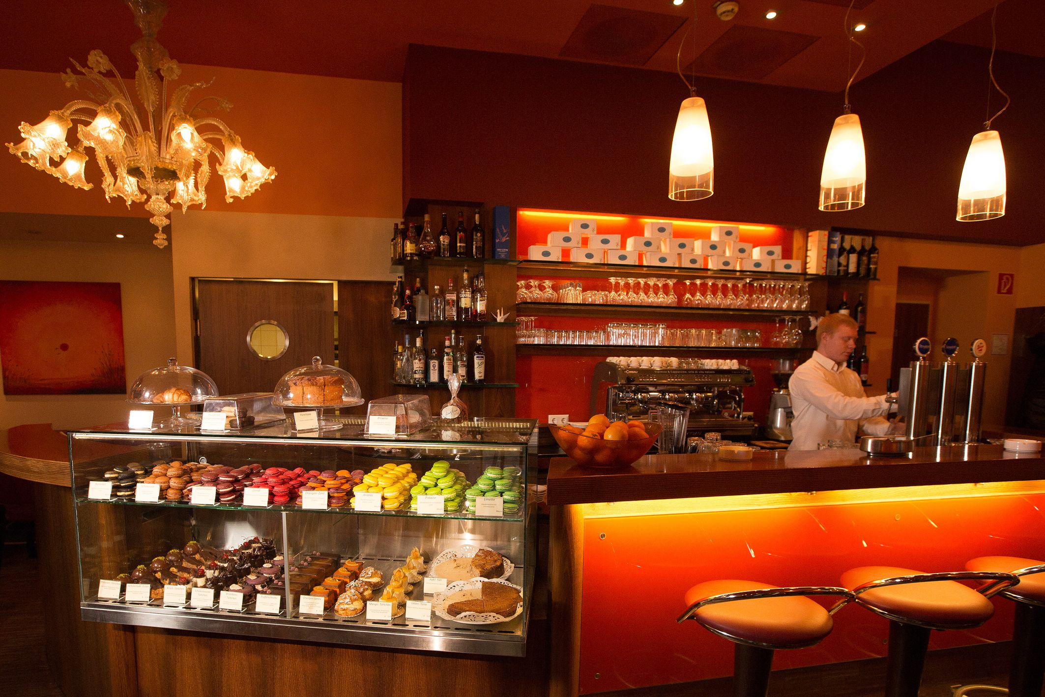 Interior view of a café with counter, bar stools and pastry display case.