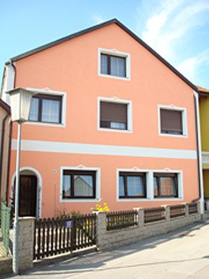 Front view of a two-storey house with orange façade and white window frames.