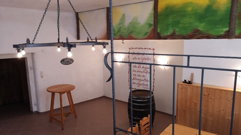 Interior view of a rustic cellar with wooden table, wine barrel and wall decoration.