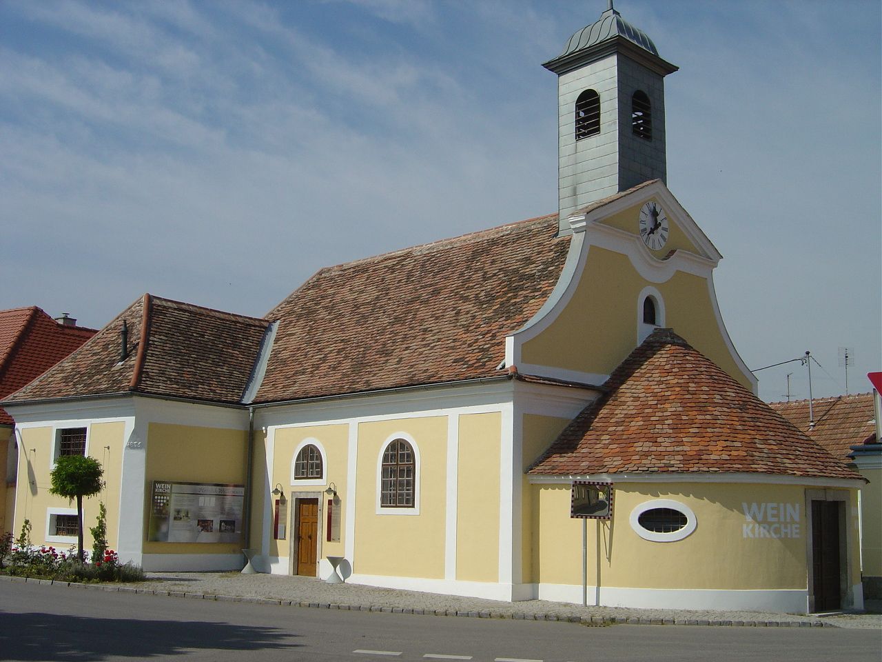 Yellow building with tower and clock, known as the wine church in Haugsdorf.