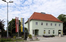 Josef Reither house with flags and bust in the foreground.