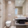 Modern bathroom with washbasin, mirror, toilet and towel rail.