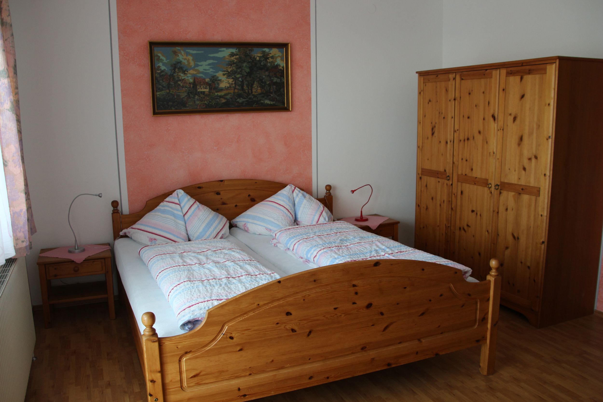 A bedroom with a double bed, two bedside tables, a closet and a painting on the wall.