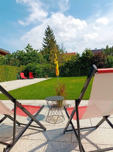 Two sun loungers in the garden with lawn and trees in the background.