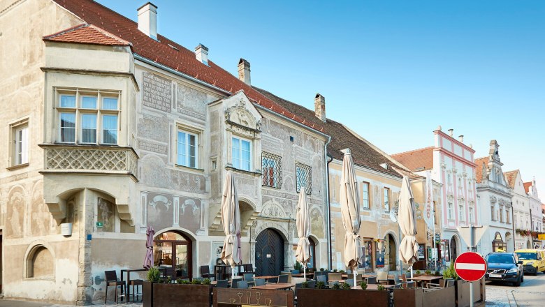 Historic buildings in Eggenburg with ornate facades and a street caf&eacute; in the foreground.