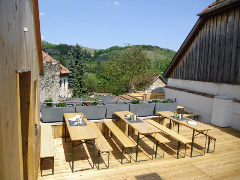 Wooden terrace with benches and tables, surrounded by rural landscape.