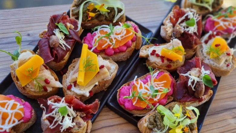 Various sandwiches on two black plates.