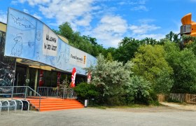 Entrance to the Fossil World with a large banner and trees in the background.