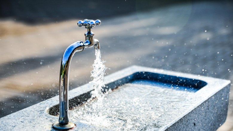 An outdoor drinking fountain with running water.