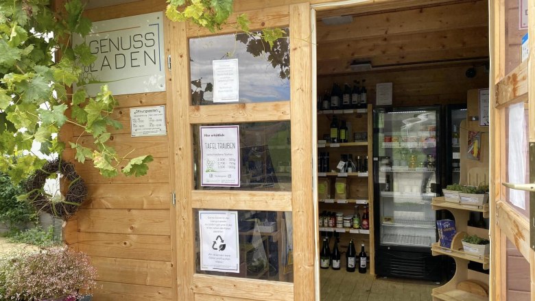 A small wooden store with grapes and drinks inside.