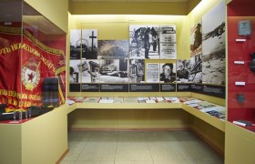Exhibition room with historical photos, documents and a red flag.