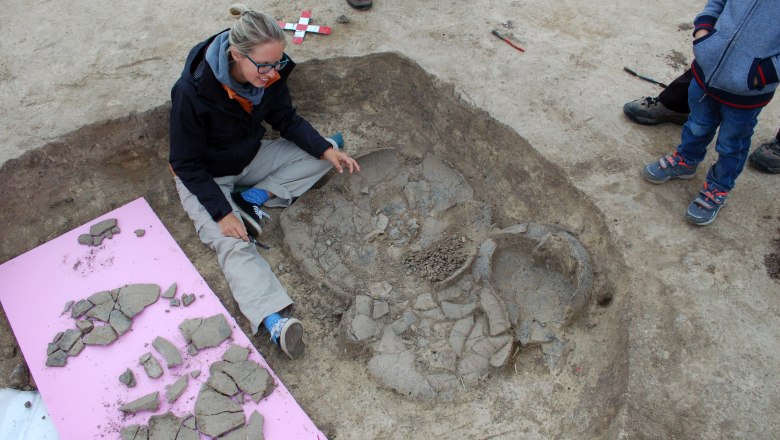 Archaeologist examines broken pottery at an excavation site.