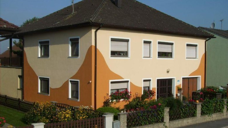 Two-storey house with orange-beige façade and garden.