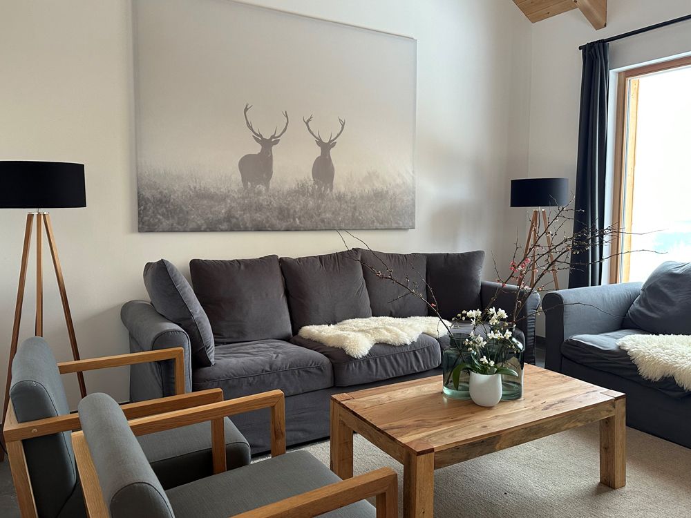 Living room with gray sofas, wooden table and deer picture on the wall.