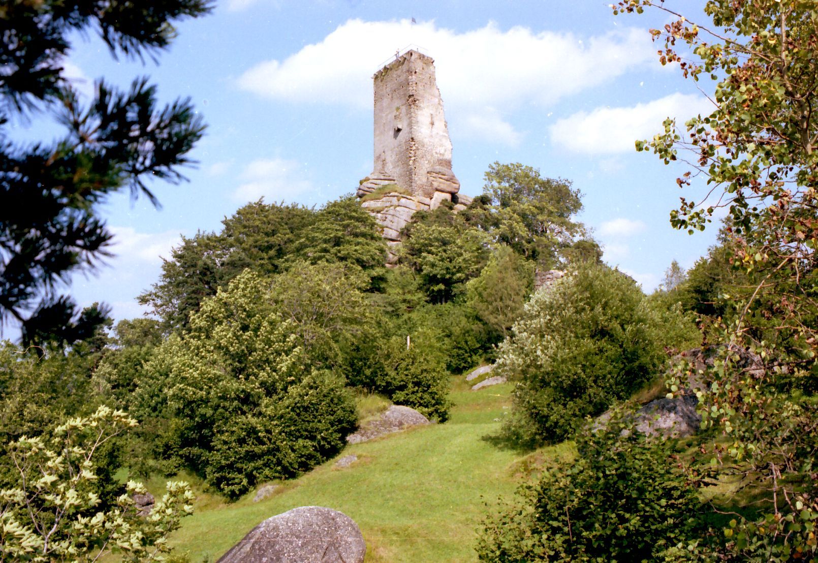 Ruin Arbesbach on a wooded hill with blue sky in the background.