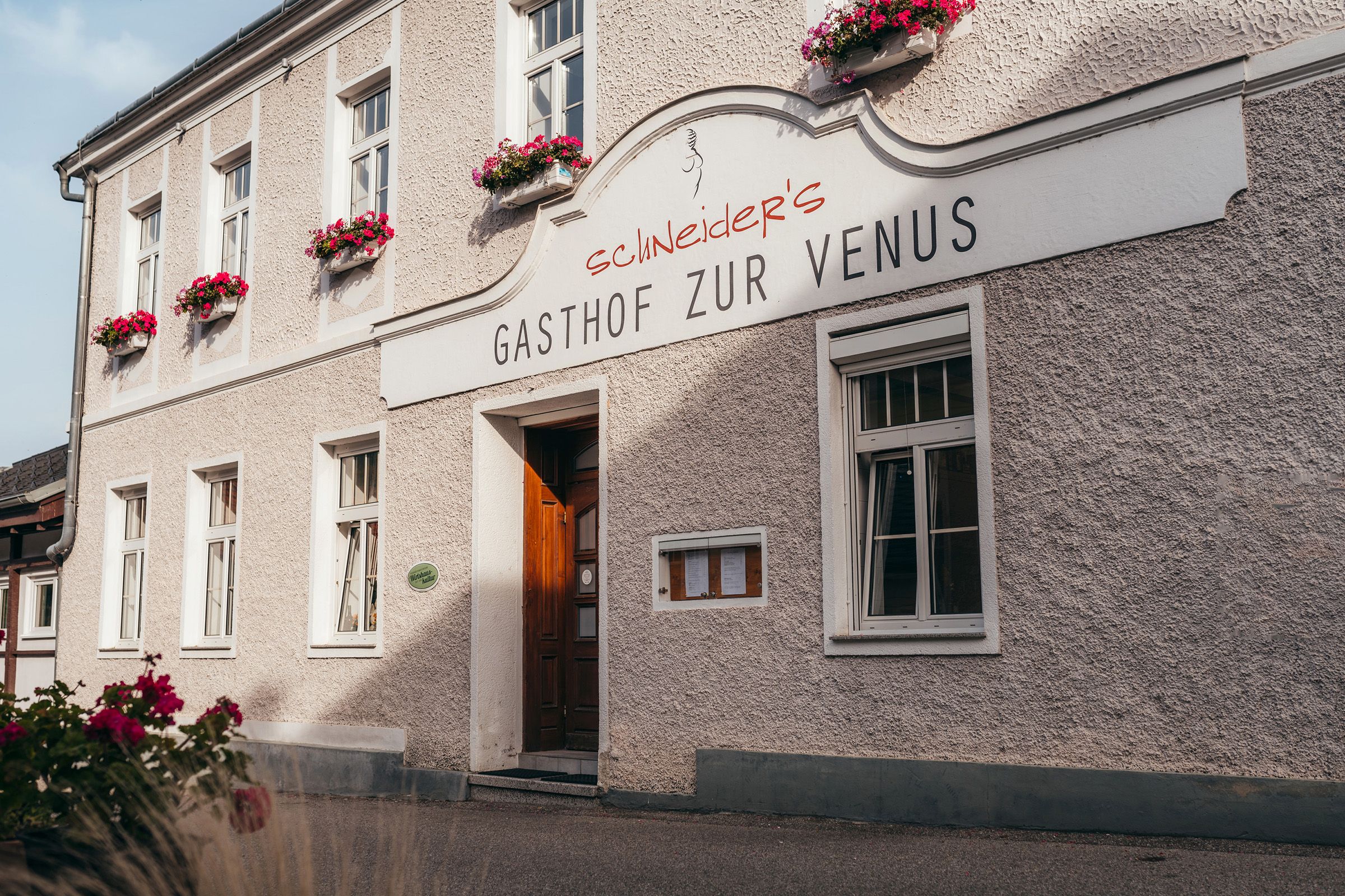 Gasthof zur Venus with flower-decorated façade and wooden door.