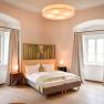 An elegant bedroom with a double bed, two windows with curtains and stylish lighting.