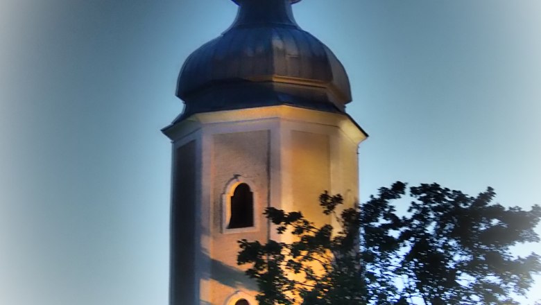 Illuminated church tower of the Sallingberg parish church at dusk.