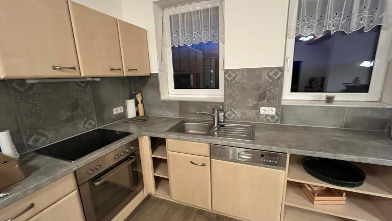 Modern kitchen with wooden cupboards, electric stove, sink and dishwasher.