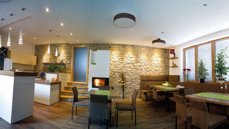 A modern tasting room with wooden furniture, stone wall, fireplace and plants.