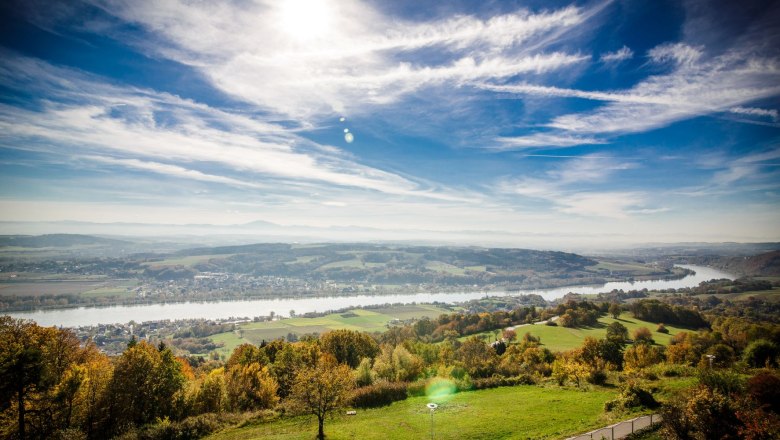 Panoramic view of a river landscape with green fields and blue sky.