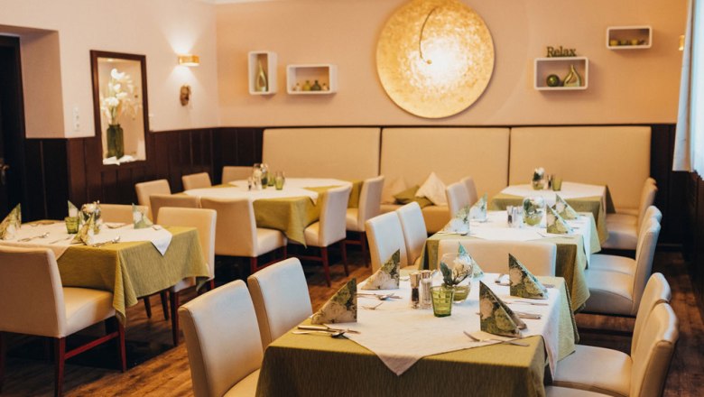 Elegant restaurant with laid tables and green tablecloths.