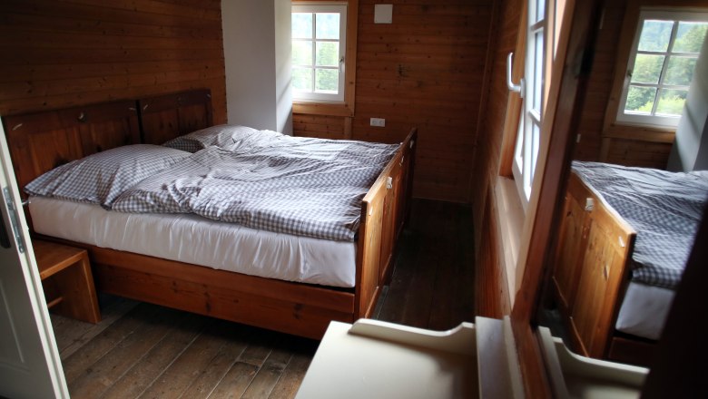 A cozy room with wooden walls and a double bed in the Vorderötscher shelter.