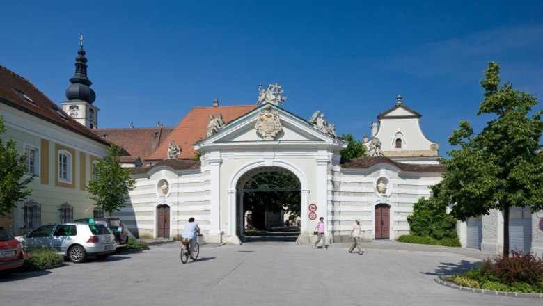Historic diocese building with archway and church tower in the background.