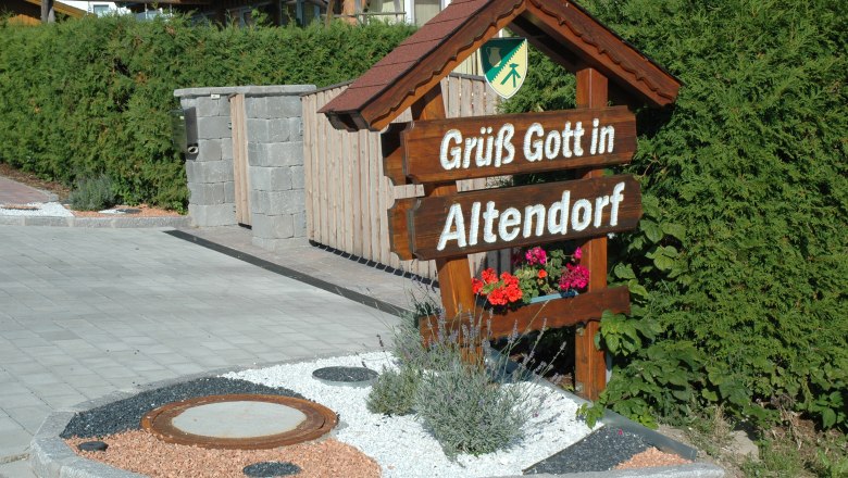 Welcome sign with the inscription 'Gr&uuml;&szlig; Gott in Altendorf' in front of a hedge.
