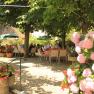 A garden with blooming hydrangeas and people sitting at tables under trees.