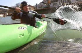 Person in green kayak paddling on a river.