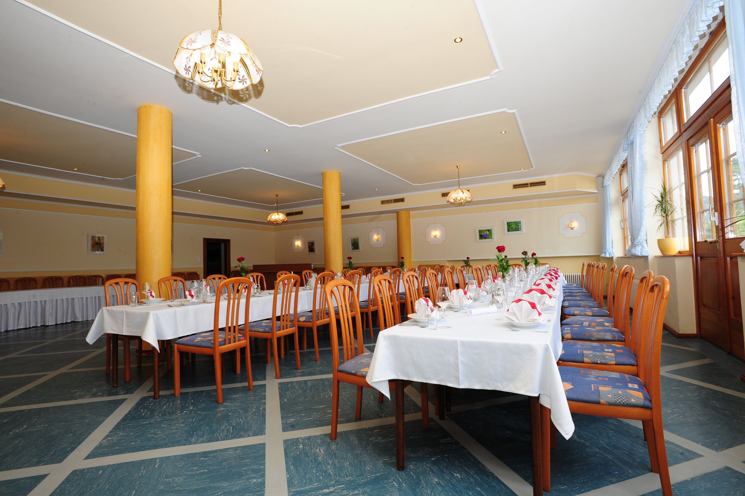 A festively decorated hall with long tables and wooden chairs, suitable for celebrations.