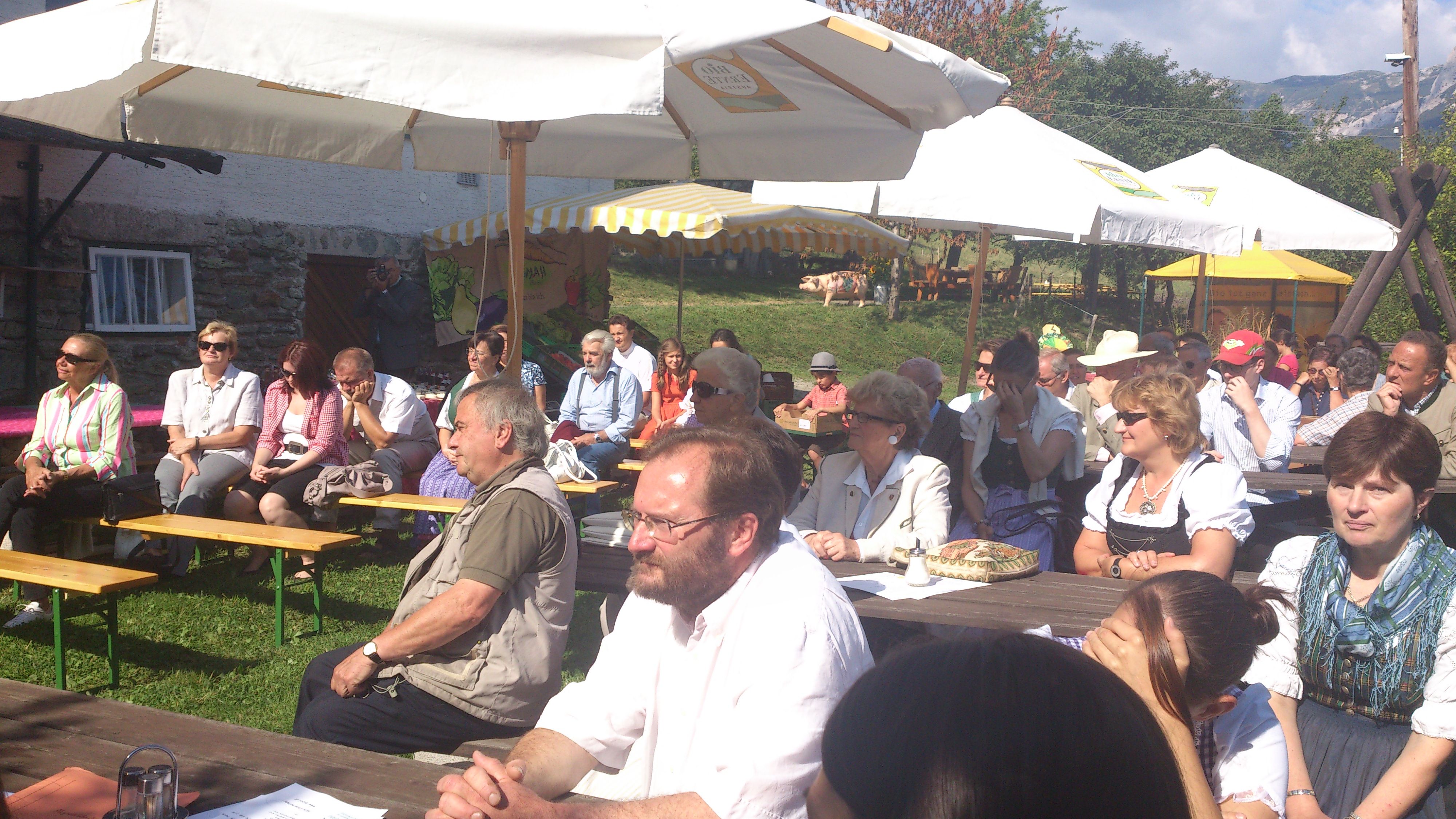 People sitting outside under parasols at an event.