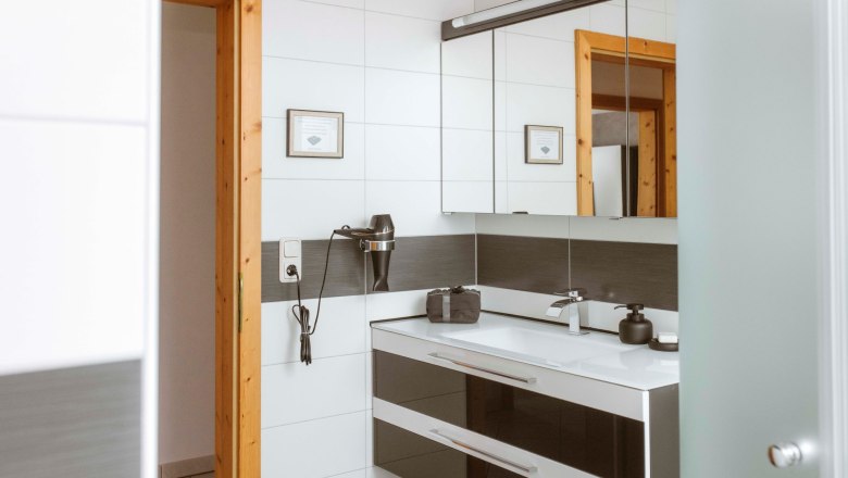 Modern bathroom with mirror, washbasin and hairdryer on the wall.